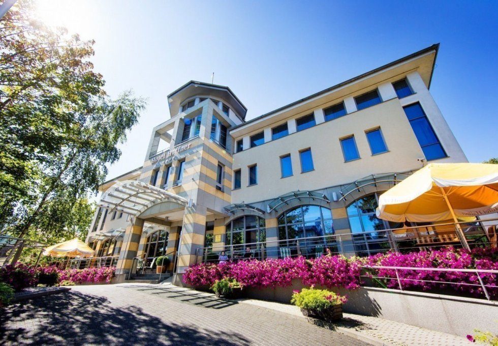 Sunny entrance of Hotel Haffner Sopot framed by bright flower beds