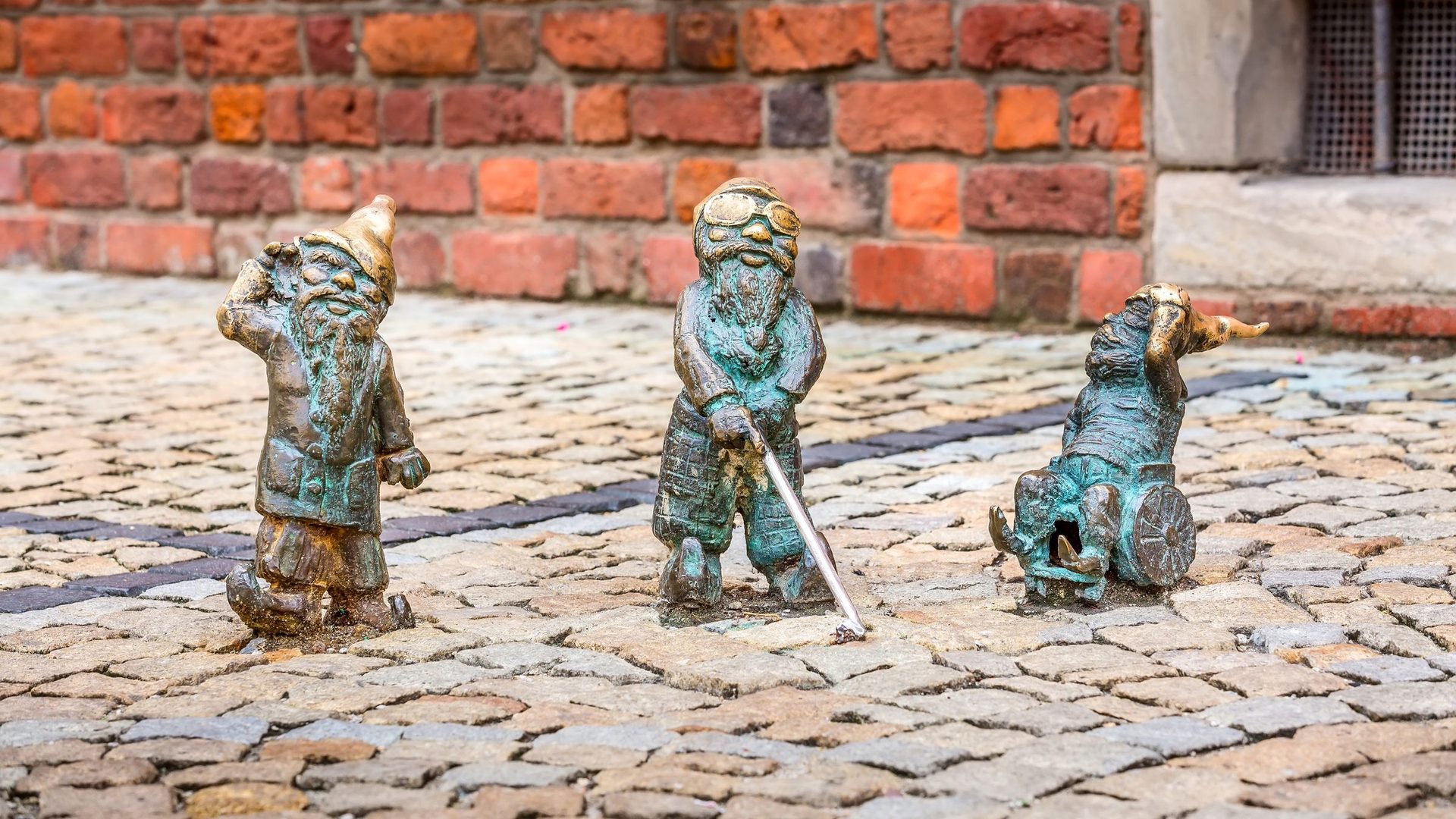 Bronze dwarf sculptures on a cobblestone street in Wrocław