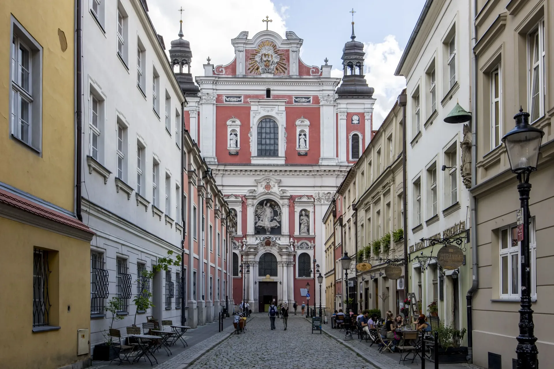 Cobblestone lane leading to the pink Baroque façade of Poznań Fara Church